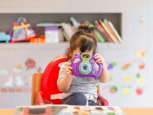 Une fillette qui tient un appareil photo jouet violet et vert