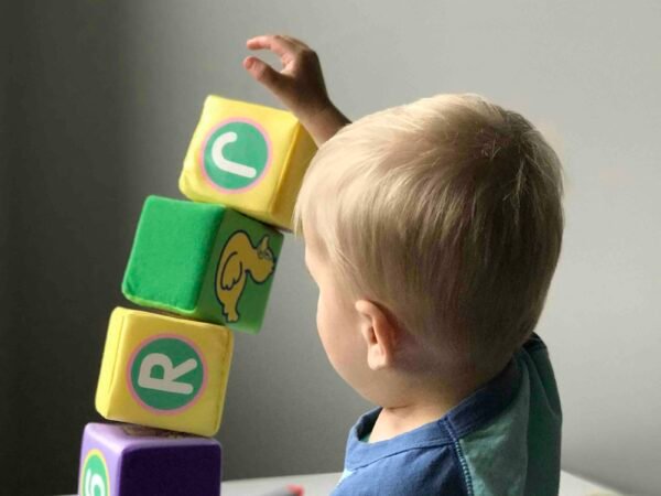 Un garçon qui manipule un cube sur une table en bois blanc